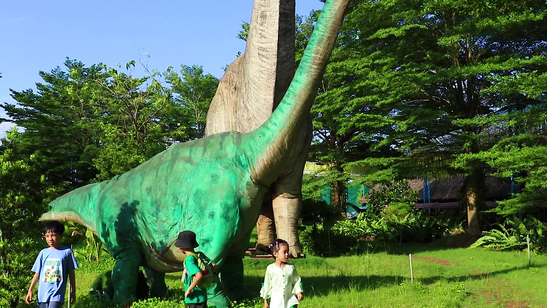 Khủng long cổ dài trong Khu Công Viên Khủng Long, các em nhỏ đi dạo bên cạnh